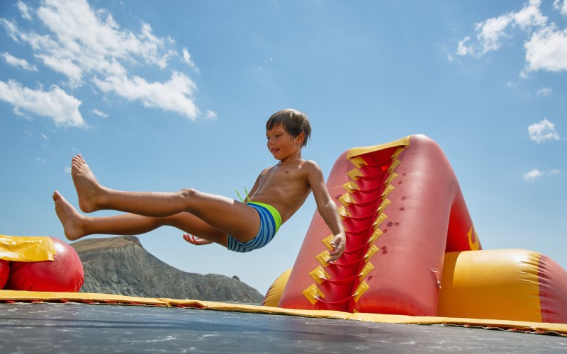 boy playing on water trampoline on the sea at sunny day